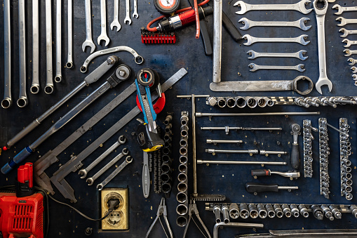 Wrenches ratchet and screwdriver in four corners on light colored background