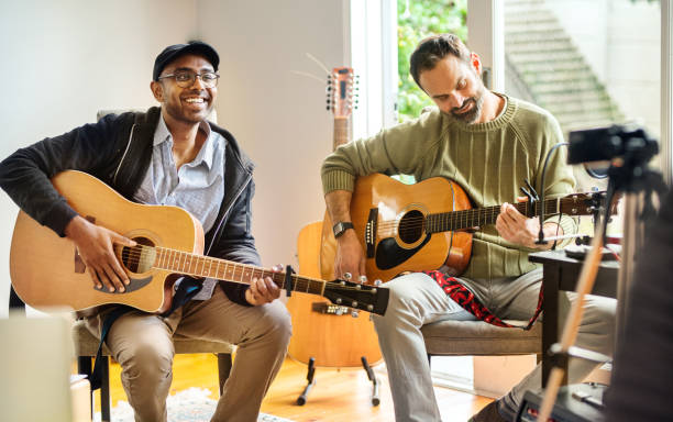 due amici sorridenti che suonano le chitarre durante una prova della band - sequenza di strumento musicale foto e immagini stock