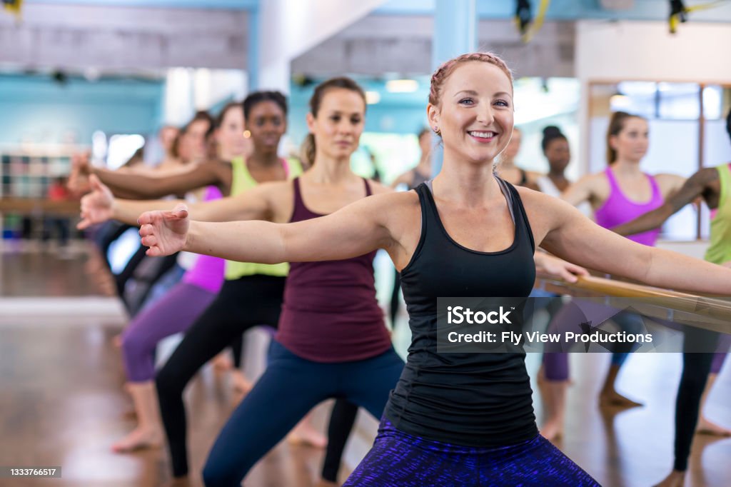 Group Barre Fitness Class A group of fit, ethnically diverse woman are working out together doing barre. They are hanging onto the barre and are on their tippy toes. Barre Stock Photo