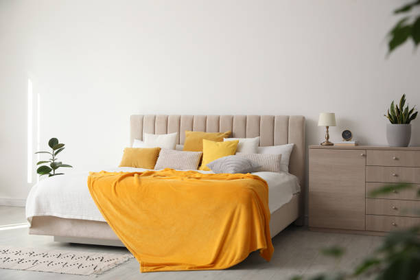 istock Stylish bedroom interior with soft yellow pillows and blanket 1333768014