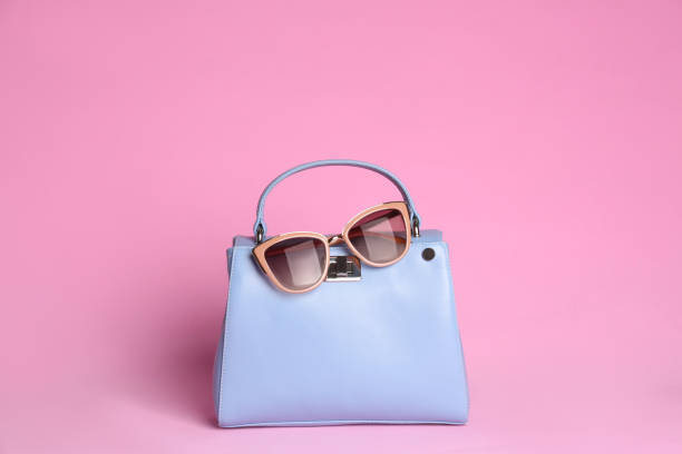 istock Stylish woman's bag and sunglasses on light pink background 1333768354