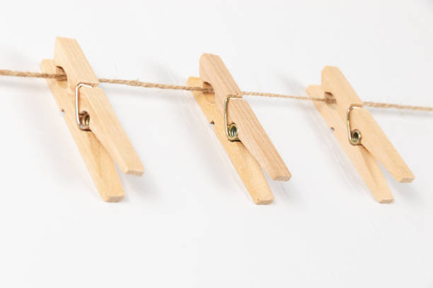 istock three wooden clothespins with a metal spring hang on a rope on a white background 1333775071