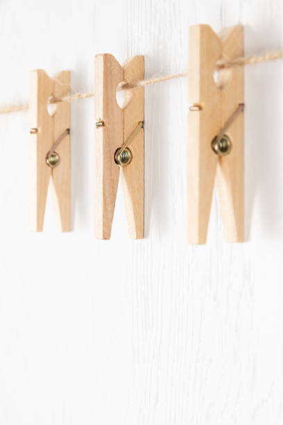 istock three wooden clothespins with a metal spring hang on a rope on a white background 1333775072