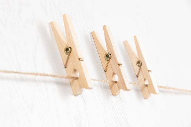 istock three wooden clothespins with a metal spring hang on a rope on a white background 1333775076