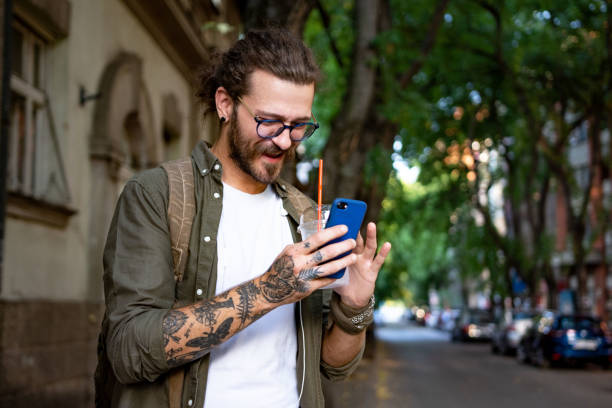istock Modern young man at the city street using smart phone 1333775416