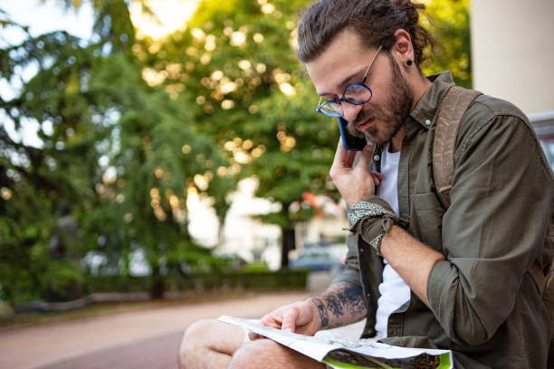 istock Tourist man holding map while talking on mobile phone 1333775726