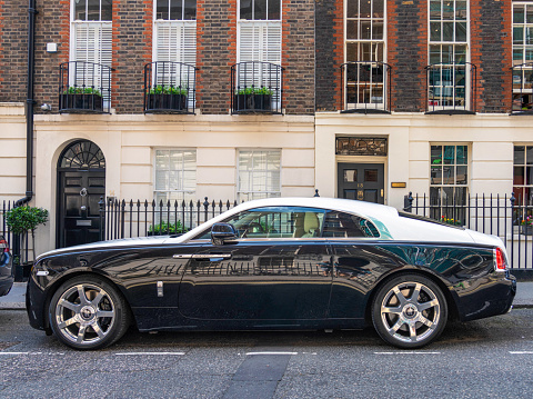 London, UK - Side view of a black and white Rolls Royce Wraith parked on a residential street in central London.