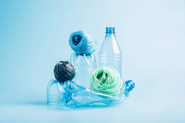istock Plastic recycling and reuse concept. Empty plastic bottle and polyester fiber synthetic thread on a blue background. 1333783691