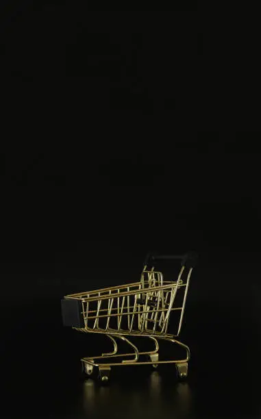 Photo of Shopping trolley on the black background with free space for text. Black friday concept. Sale, deal and discount. Closeup, copy space.