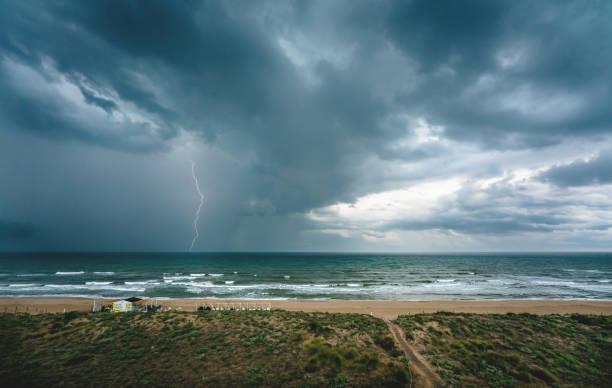 Lightning flash and dark thunderstorm over the ocean along the Mediterranean coast in Daimus, Spain