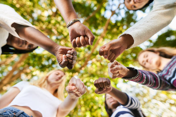 Teenage girls standing with fists in a circle before an equality protest Low angle of a group of diverse teenage girls standing together in a circle with their fists together during a women's rights protest gender equality stock pictures, royalty-free photos & images