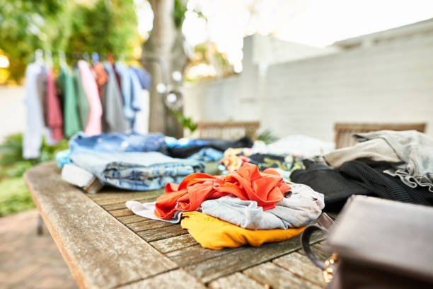 Second hand clothing for sale at a garage sale Assortment of second hand clothing lying on a table and hanging on a rack at a garage sale clothing swap photos stock pictures, royalty-free photos & images