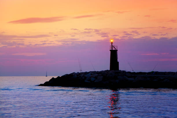 istock Sunrise lighthouse glowing in blue purple sea 1333791879