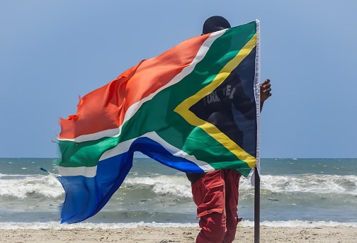 Africa Ghana man standing behind a South Africa flag on a beach in Labadi beach Accra Ghana West Africa 2018 April 16