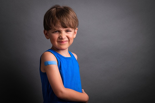 Angry crying Caucasian Six years old child just after being vaccinated  wearing a band aid on his arm