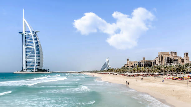 Luxurious Burj Al Arab hotel in Dubai, United Arab Emirates. Dubai, UAE - May 31, 2013 The Burj Al Arab hotel on a sunny day with people in the shore. jumeirah stock pictures, royalty-free photos & images