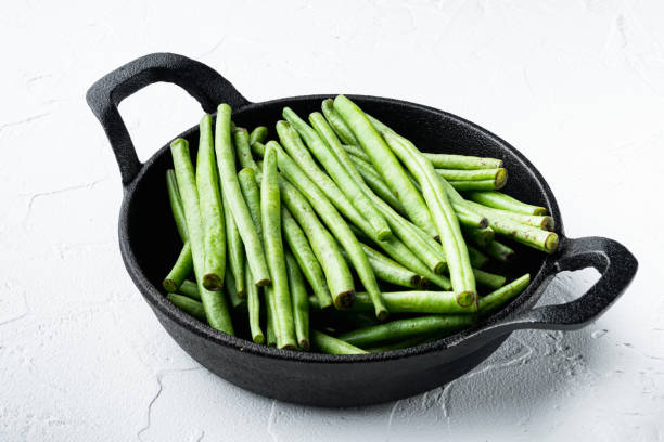 istock Green string bean, in frying cast iron pan, on white stone  background 1333802917