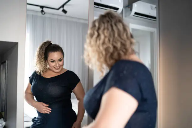 Photo of Pretty woman getting dressed in front of a mirror at home