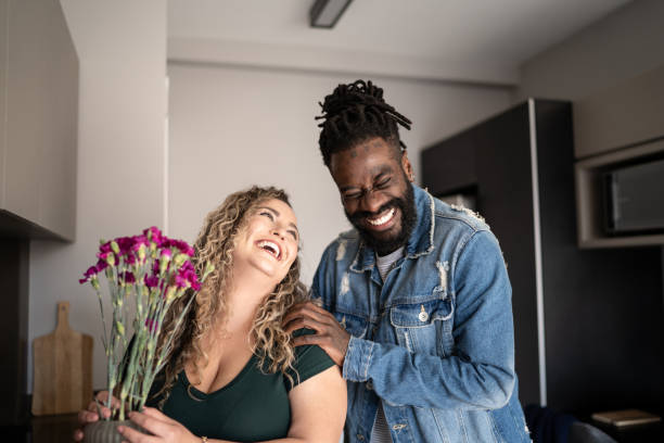 happy woman with bouquet of flowers from husband at home - men african descent giving flower imagens e fotografias de stock