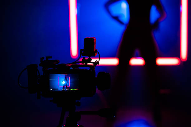istock Backstage how operator working with professional camera. Videographer shoots clip with woman dancing in dark studio with neon color light lamps. 1333807952