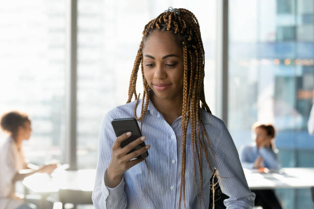 молодая африканская этническая бизнесвумен с использованием приложений для мобильных телефонов. - women dependency business time стоковые фото и изображения