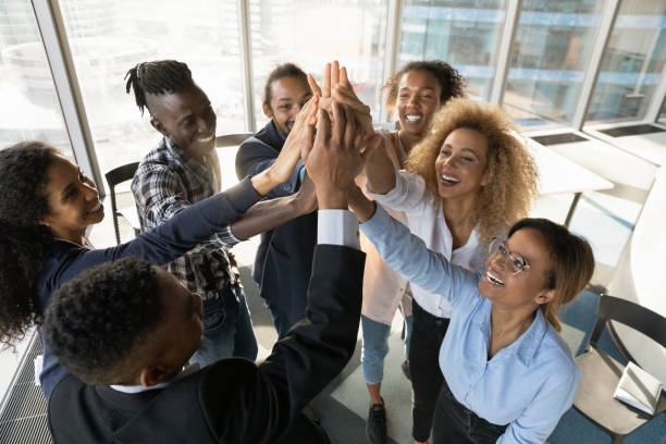 Friendly young african colleagues joining hands in air. Above top view happy friendly young african american diverse colleagues joining hands in air, celebrating shared corporate success, effective teamwork, raising working spirit, teambuilding concept. person of color stock pictures, royalty-free photos & images