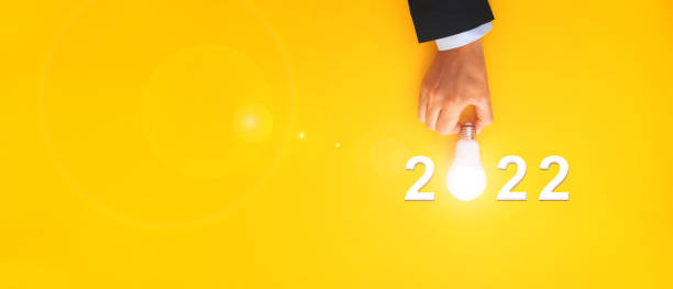 istock Business plan, solution and strategy with inspiration idea in year 2022. Businessman holding light bulb with year 2022 plans and copy space on yellow background. 1333810779