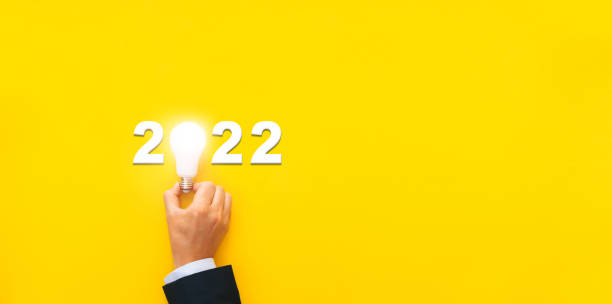 istock Business plan, solution and strategy with inspiration idea in year 2022. Businessman holding light bulb with year 2022 plans and copy space on yellow background. 1333810780