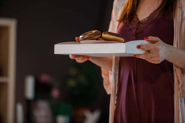 istock Young woman holding a tray with doughnuts 1333812533