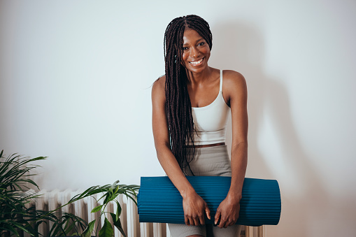 Happy African-American woman in sportswear standing ready for workout session or yoga training at home