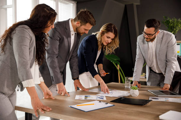 istock Four business people looking at charts and graphs on documents during a meeting 1333814011