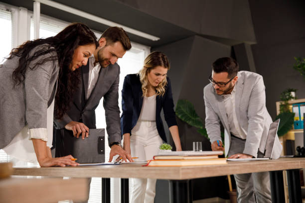 istock Four business people standing around a conference table, planning out a project 1333814017
