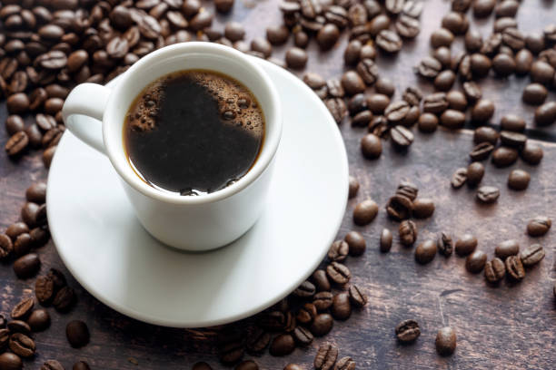 White cup with strong black coffee on a rustic wooden table with some beans, copy space, selected focus White cup with strong black coffee on a rustic wooden table with some beans, copy space, selected focus, narrow depth of field arabica coffee drink stock pictures, royalty-free photos & images