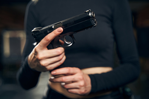 Cropped photo of a professional Caucasian woman military holding a loaded pistol with both hands