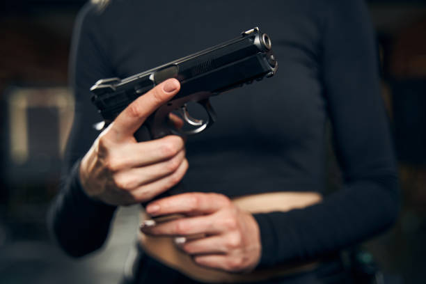 Female preparing for a shooting drill indoors Cropped photo of a professional Caucasian woman military holding a loaded pistol with both hands female sharp shooter stock pictures, royalty-free photos & images