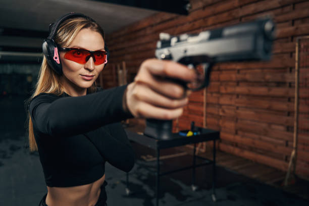 tirador experimentado nivelando su arma a un objetivo - gun women handgun armed forces fotografías e imágenes de stock