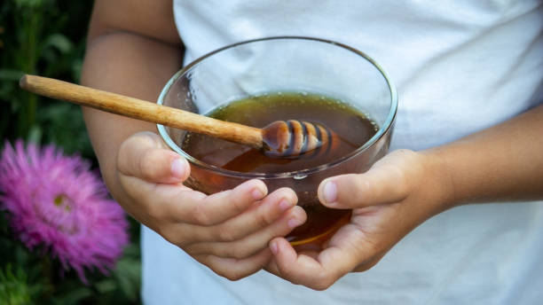 istock A child eats honey in a flower garden. Selective focus 1333817095