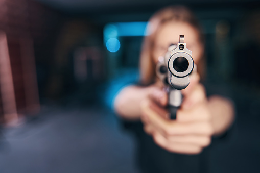Blurred photo of an experienced female shooter holding a revolver with both hands in front of her
