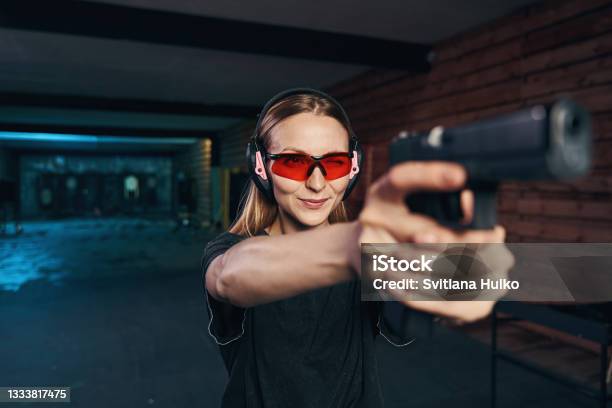 Young Woman Concentrated On Shooting At A Target Stock Photo - Download Image Now - Target Shooting, Gun, Women