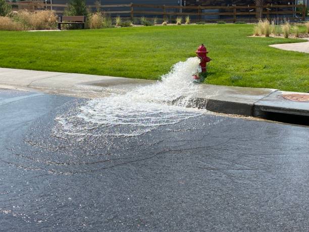 Water from a hydrant with sewer cover Fire hydrant with water pouring into the street flushing water stock pictures, royalty-free photos & images