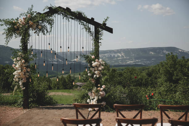 istock Wedding arch on boho style with white flowers in park with light bulbs. 1333820695