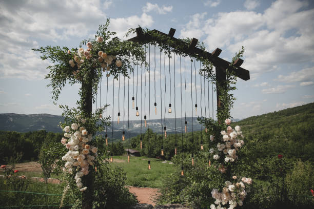 istock Wedding arch on boho style with white flowers in park with light bulbs. 1333820783