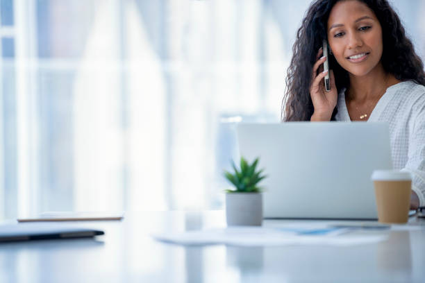 istock Attractive woman working on a laptop computer and talking on a mobile phone. 1333820973