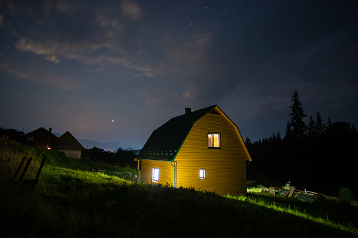Night landscape, wooden house in a village near the forest in the Carpathian mountains
