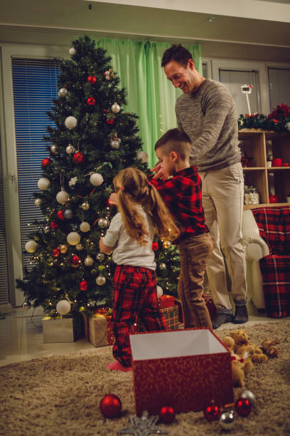 istock Kids helping their father put Christmas lights on a Christmas tree 1333823843
