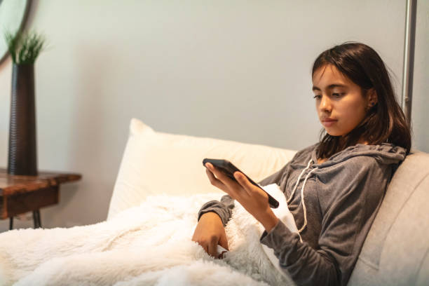 istock Generation Z Female Sitting On Living Room Couch Using Smart Phone Technology During Sickness Colombian American Photo Series 1333828116