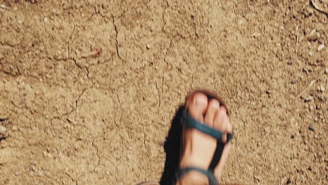 Caucasian Male Wearing Black Leather Sandals Walking on Dusty Dry Ground Road during Summer Drought