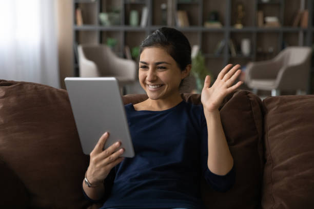 istock Young hindu woman make videocall wave hand hi using pad 1333838095