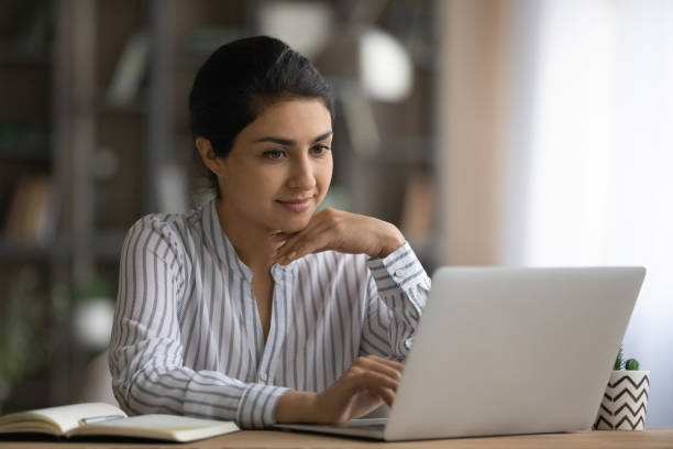 istock Confident young indian woman worker sit at table by laptop 1333838159
