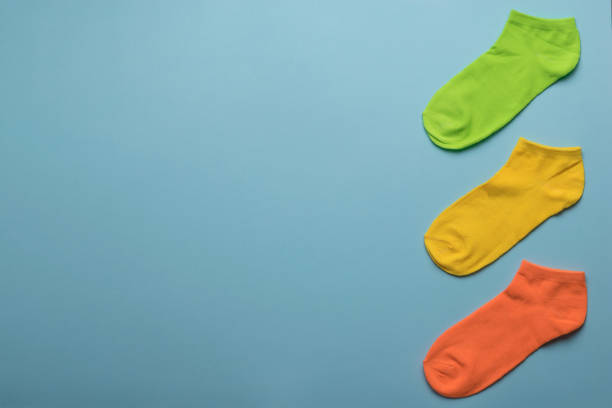 istock Orange, green and yellow socks on a blue background. Space for the text. 1333852705